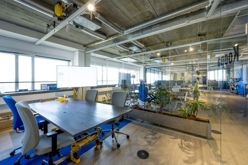 Moderne vergaderruimte in een open kantoor aan de Johan Huizingalaan met glazen wanden, planten en industriële plafondafwerking.